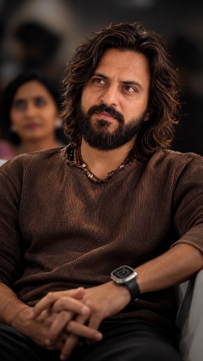 A candid portrait of a man with long wavy hair sitting indoors in an audience Diinesh Patel AI Prompt Visual